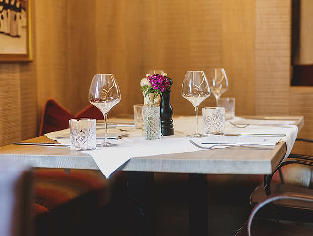 Eleganter Tisch im Restaurant mit Weingläsern, Blumen und einer einladenden Atmosphäre