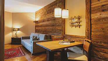 Sitzgelegenheit in der Suiter, bestehend aus einem Tisch und zwei Stühlen vor einer Holzwand