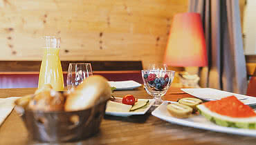 Ein gedeckter Frühstückstisch mit Orangensaft, Beeren, Gebäck und Dekoration im Hotel Auhof