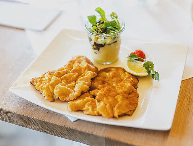 Frisch serviertes Schnitzelgericht mit Beilagen auf einem weißen Teller im Wirtshaus
