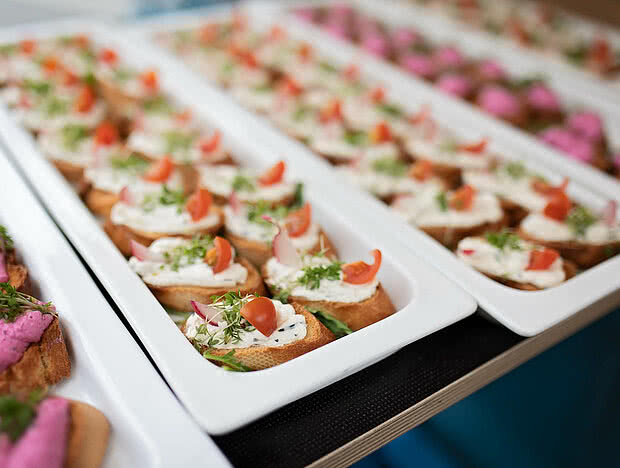 Nahaufnahme von belegten Broten mit Kresse, Radieschen und Tomaten auf weißen Platten serviert