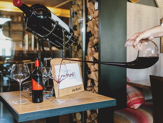 Weinverkostungstisch mit großer Weinflasche im Halter und mehreren Weingläsern in einem Gasthaus
