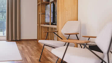 Zwei Designer Stühle vor einem Regal mit Fernseher und Dekorationen in einem gemütlichen Raum