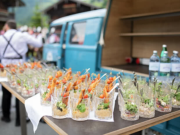 Foodtruck mit mehreren Gläsern, die mit Salaten und frittierten Snacks gefüllt sind, im Vordergrund