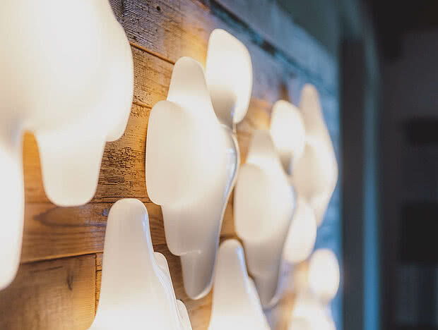 Moderne Wandbeleuchtung auf einer Holzverkleidung im Hotel Auhof